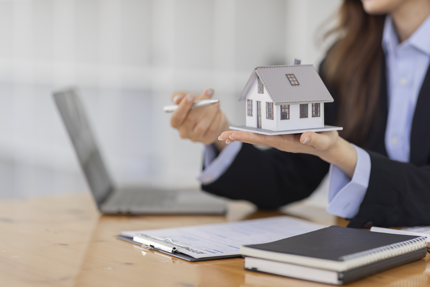 Haus verkaufen kleines Holzhaus in der Hand einer Immobilienmaklerin