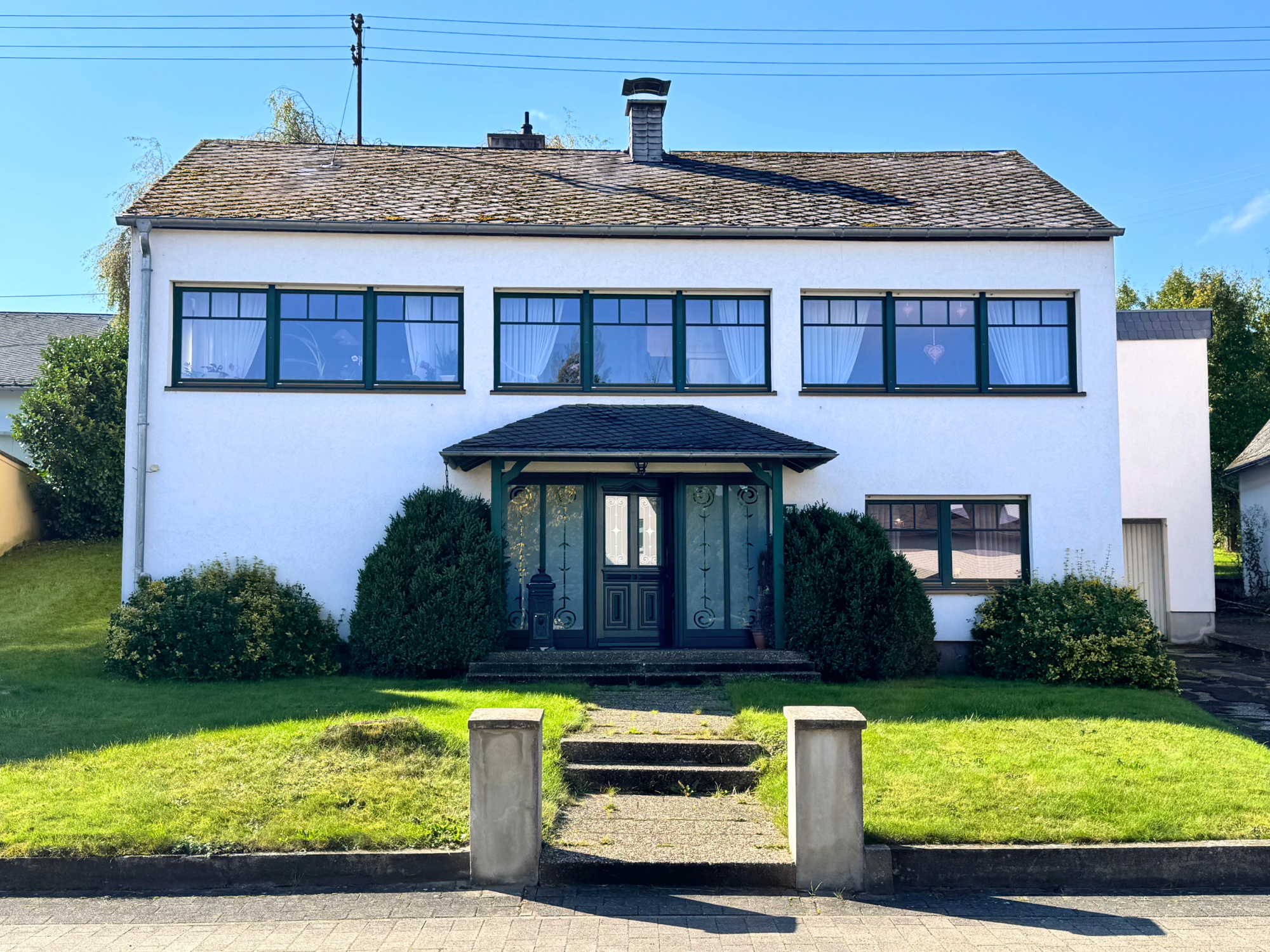 Frontalansicht EFH Frontalansicht eines freistehenden Wohnhauses in Alterkülz mit gepflegter Fassade, Vorgarten und Eingangstür