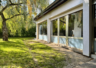 Blick vom Garten auf die große Fensterfront des Wohnzimmers im Einfamilienhaus in Alterkülz – moderne Architektur mit viel Tageslicht