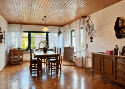 Lichtdurchflutetes Esszimmer mit großzügiger Fensterfront zur Vorderseite – stilvoller Raum für gemeinsame Mahlzeiten