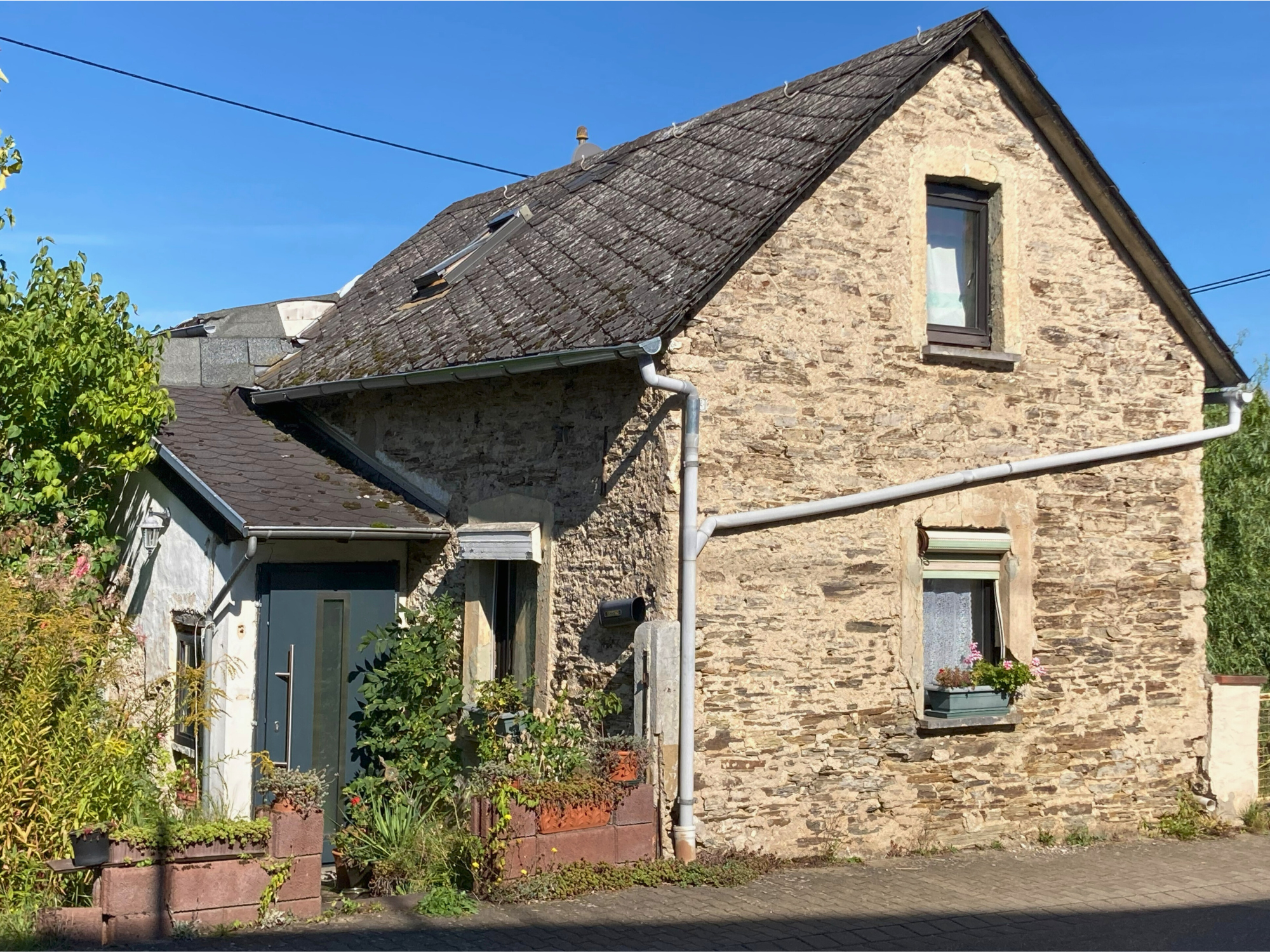 Straßenansicht Kleines Einfamilienhaus aus den 1900er-Jahren mit Satteldach und bepflanztem Vorgarten – straßenseitige Ansicht mit historischem Charme