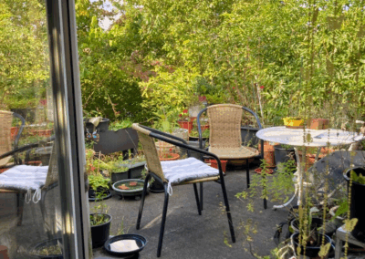 Blick von der Terrassentür nach draußen auf die Sitzecke auf der Terrasse und den Garten