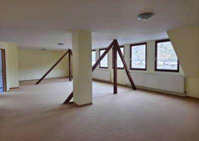 Studio im Dachgeschoss mit dunklen Holzbalken und Blich auf den Rhein und St. Goarshausen, vom Eingang ausgesehen.